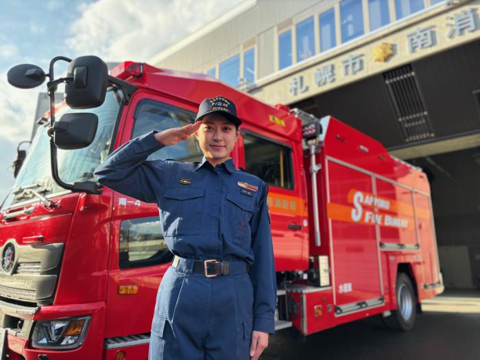 消防車両の前で敬礼する消防吏員