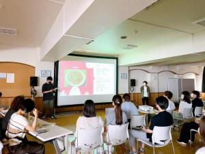 令和4年7月8日提案するレシピをグループごとに発表する学生とその発表を聞く学生たち(全3枚)