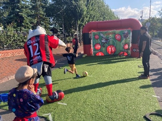 子供がお祭りでサッカーの的あてゲームをしている写真