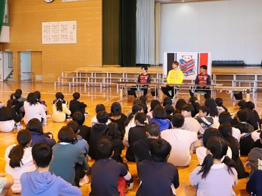 コンサドーレ札幌の選手が体育館で子どもに話をしている写真