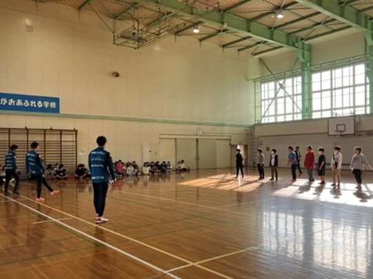 コンサドーレ札幌の選手が体育館で子どもとサッカーのパスをしている写真