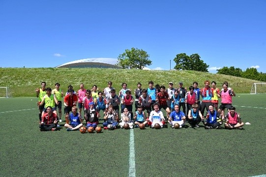 サッカー場で大人が集合している写真