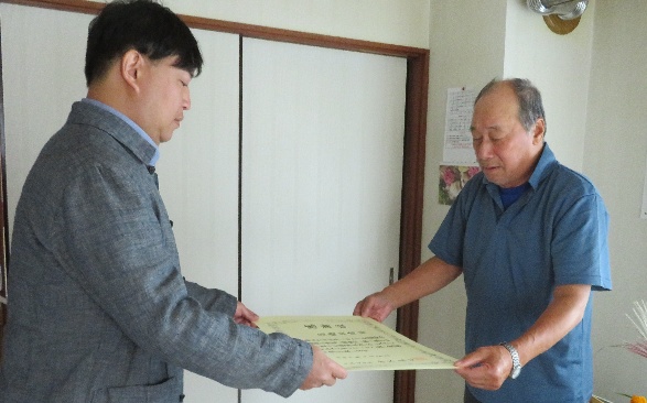 区職員から表彰状を伝達される高橋さん