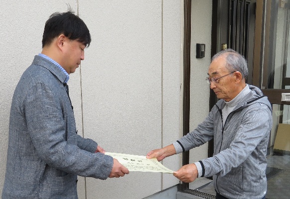 区職員から表彰状を伝達される山下さん