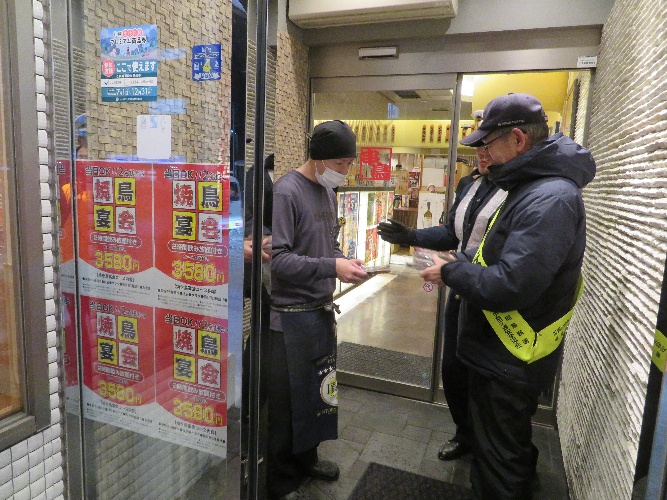 死亡事故現場付近の飲食店への啓発品配布の様子