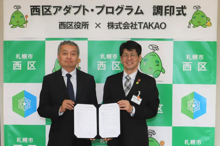 記念写真（左：高尾代表取締役、右：村上西区長）