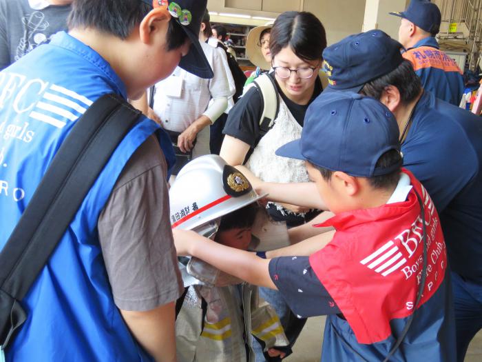 クラブ員が小さい子どもに防火帽を被せている様子